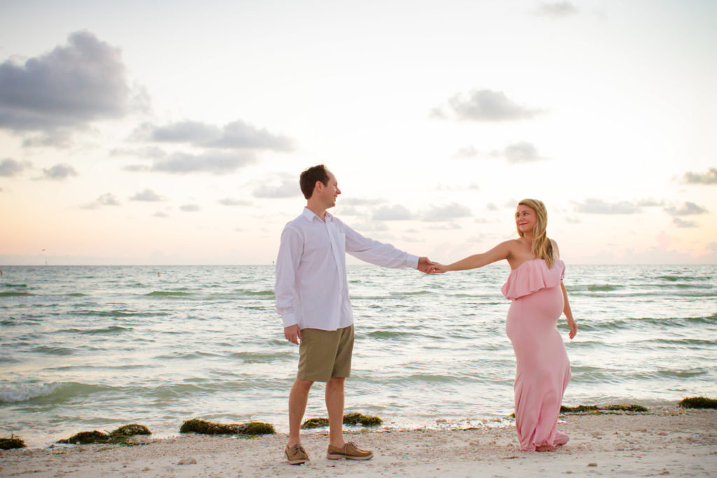 expecting couple walking the beach