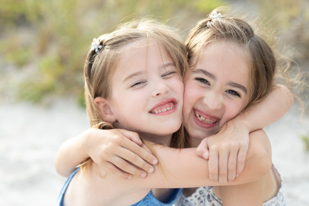 twin girls hugging at the beach