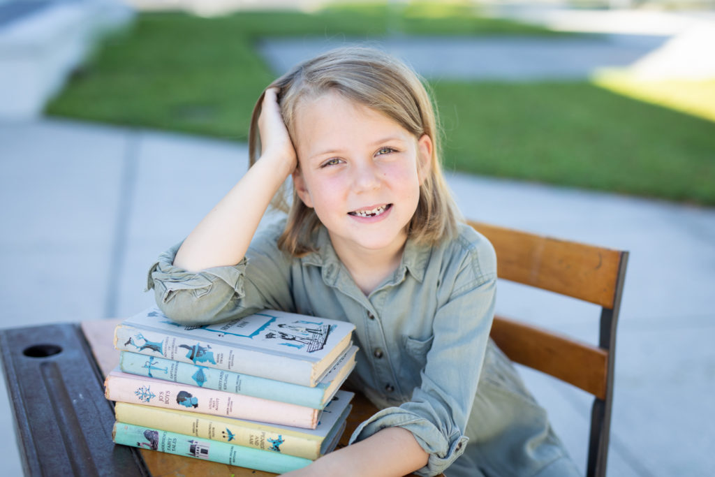 girl sitting in old fashion desk with vintage books