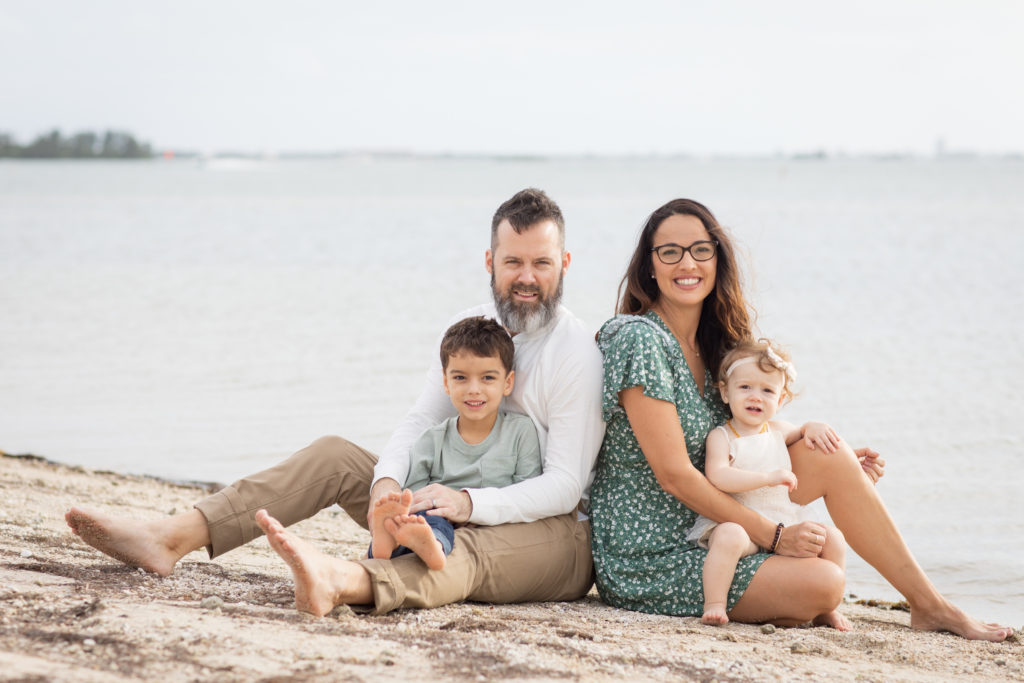 family of 4 sitting at the beach