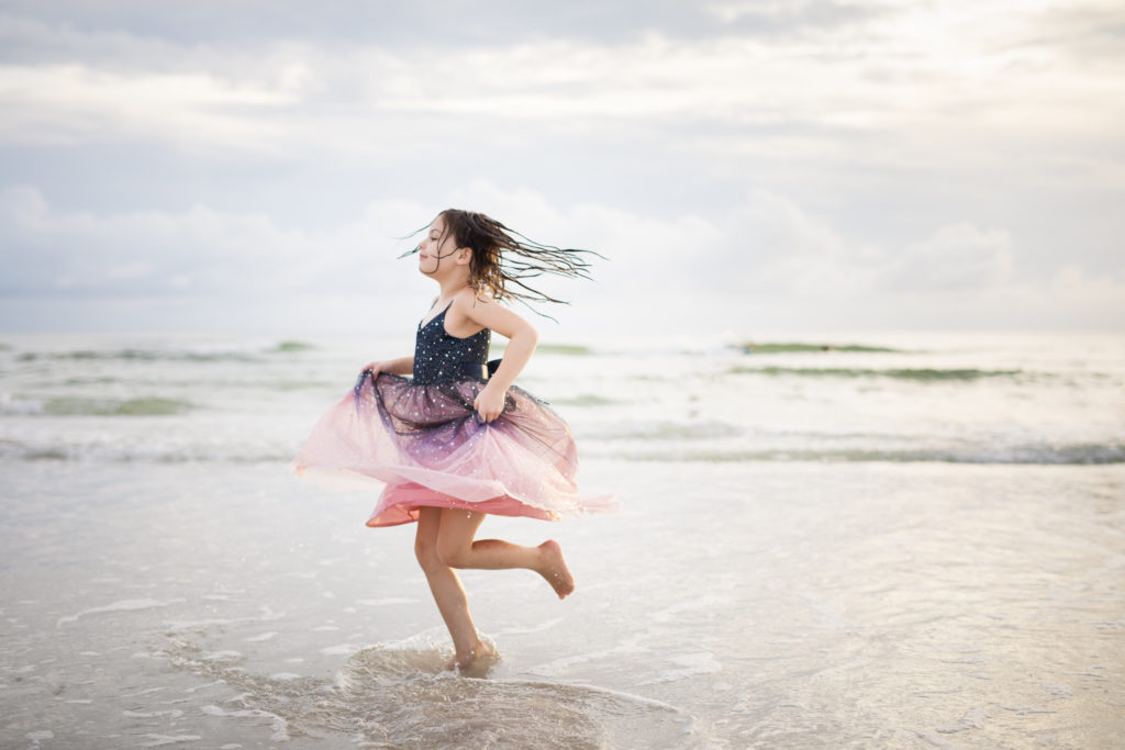 girl twirling in dress in the ocean
