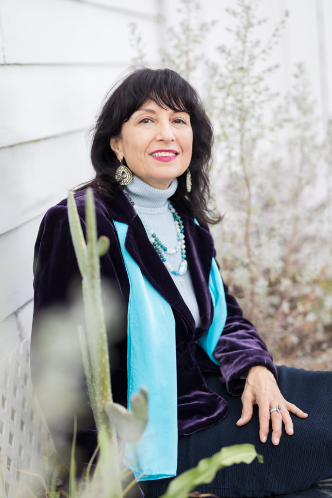 woman sitting with plants in foreground and background