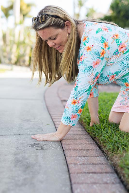 woman putting her hand next to handprint in cement