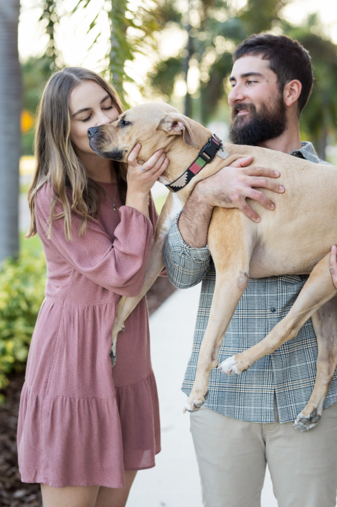 Man holding dog up for wife to kiss