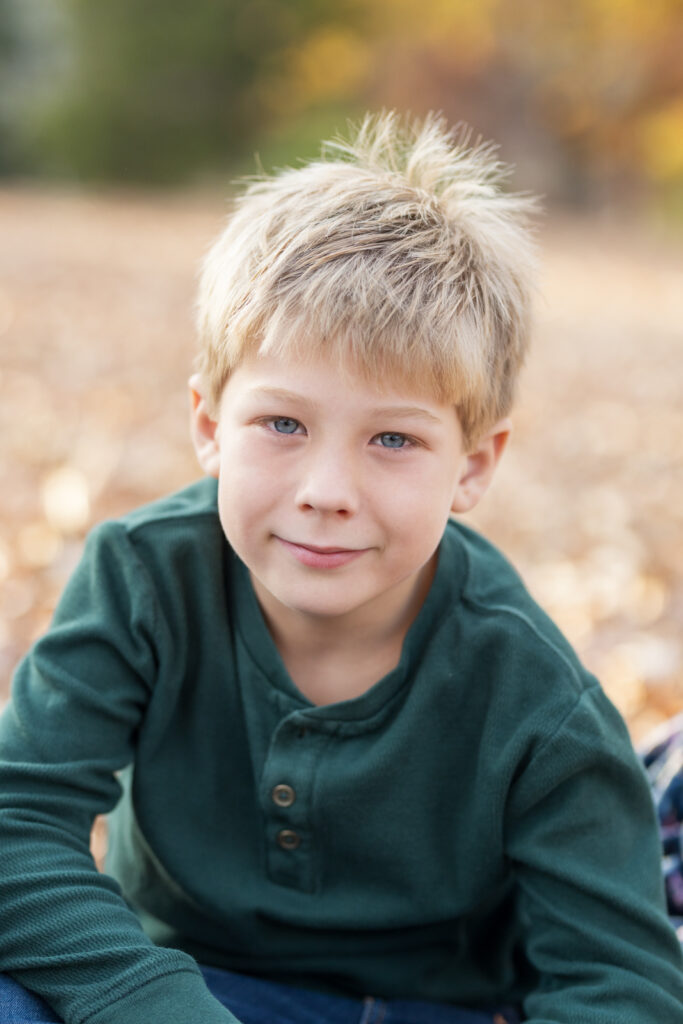 child portrait photographer tampa boy in green shirt in fall leaves