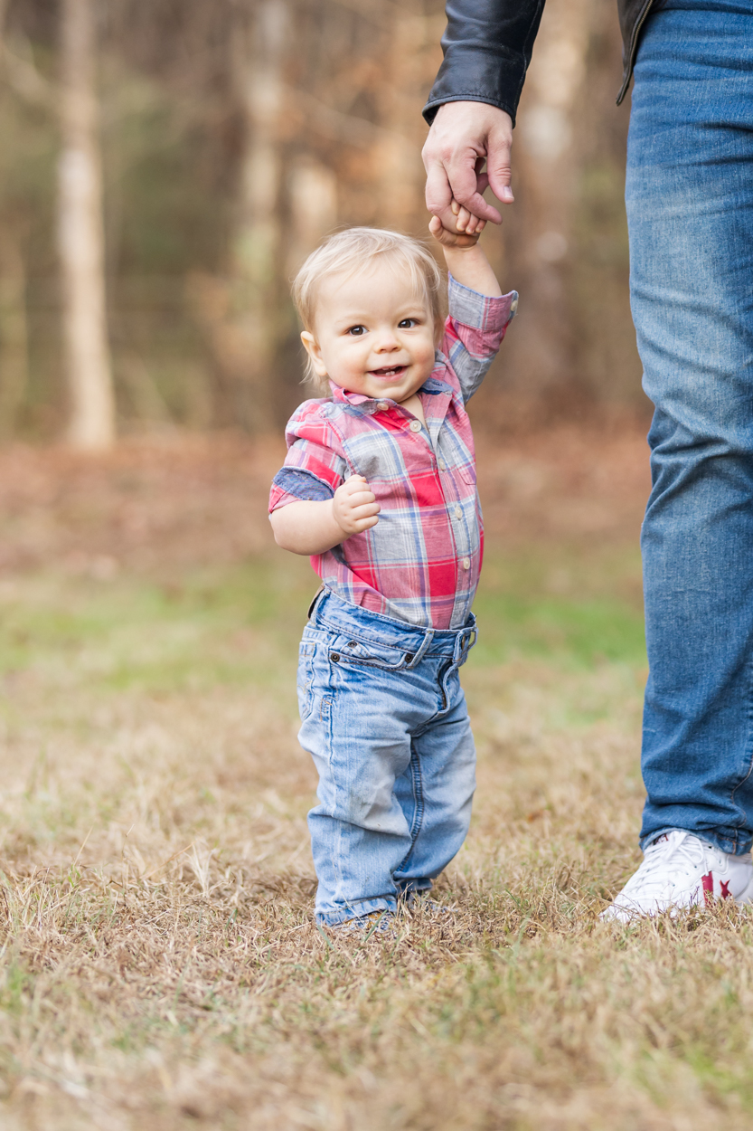 one year old boy standing with dad's help