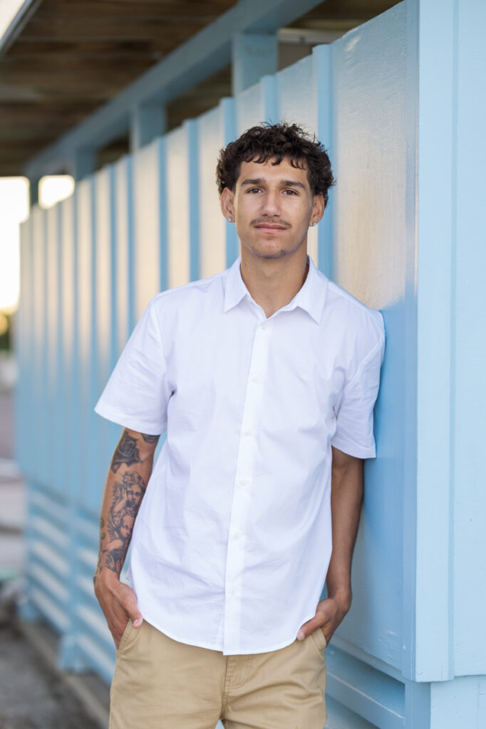 guy at beach leaning on blue wall
