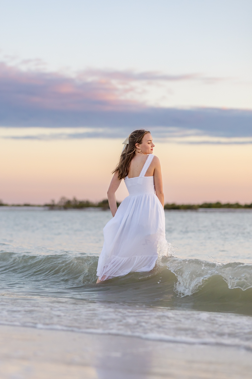 girl in gown walking into ocean