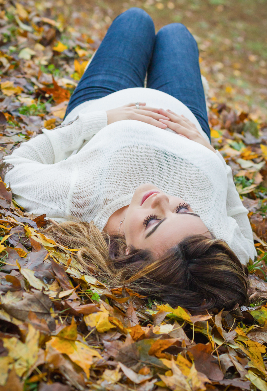 pregnant woman laying in fall leaves