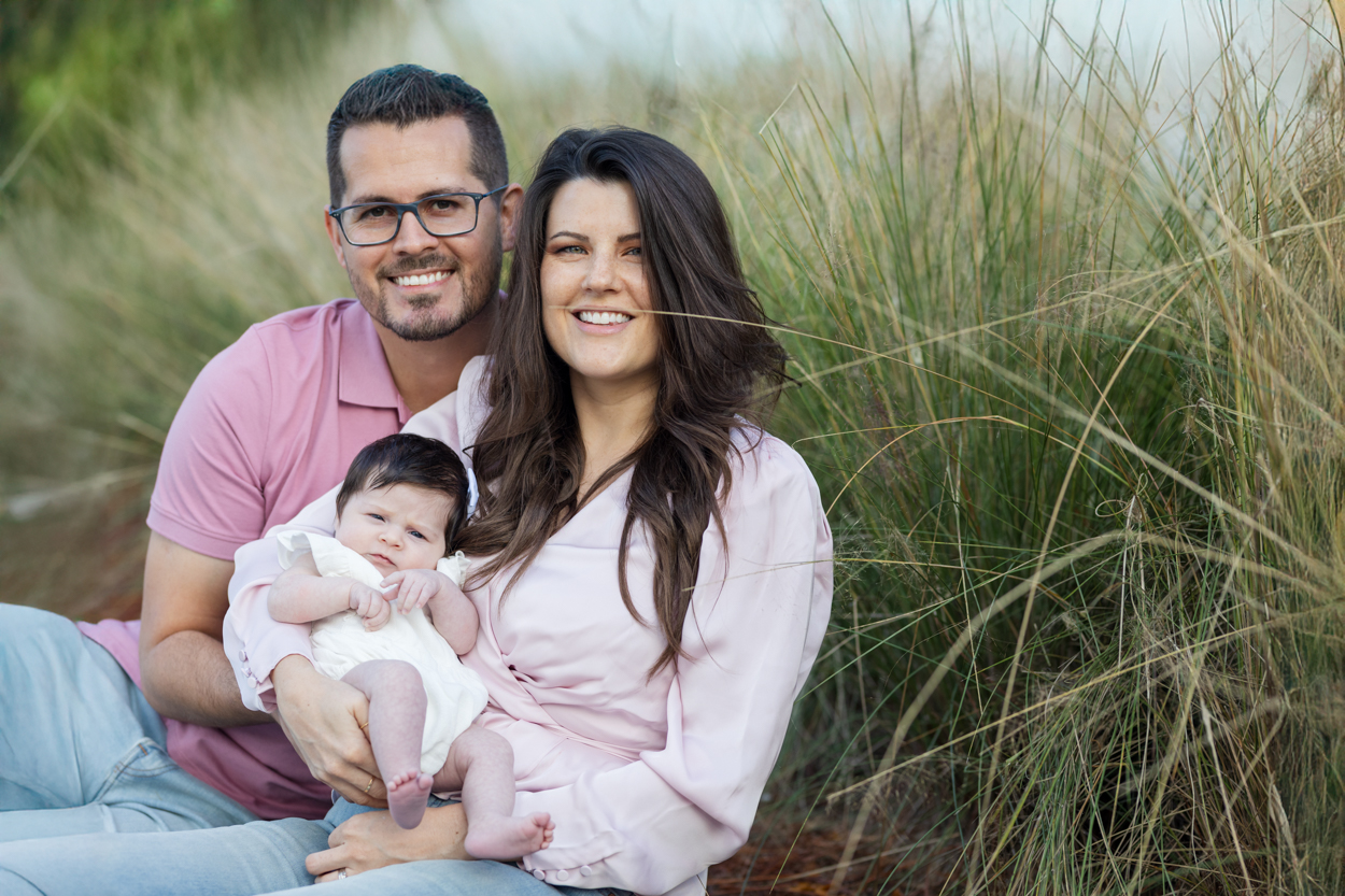 Mom and dad posing with newborn girl outdoors