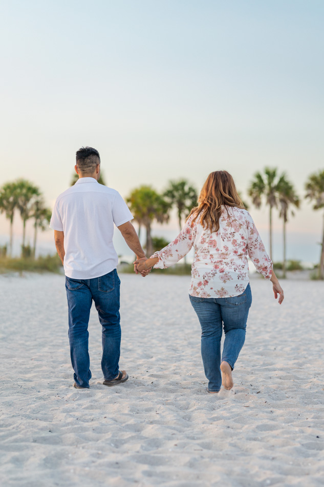 couple holding hands walking down the beach