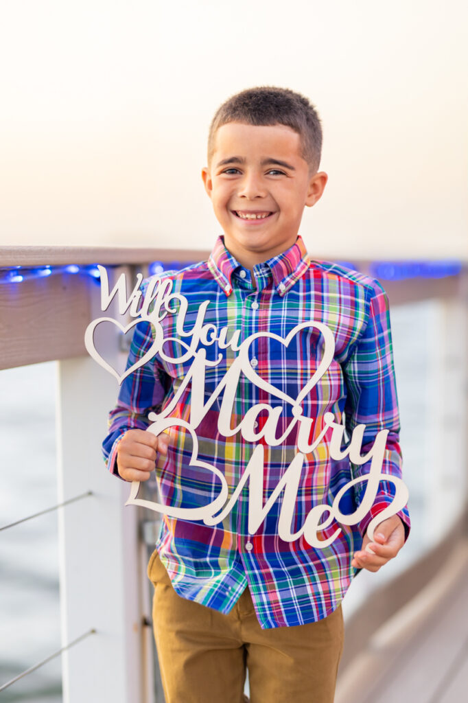 boy holding sign saying "will you marry me?"