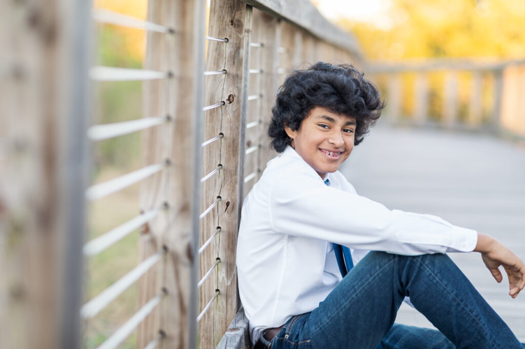 boy sitting on the boardwalk for a photo