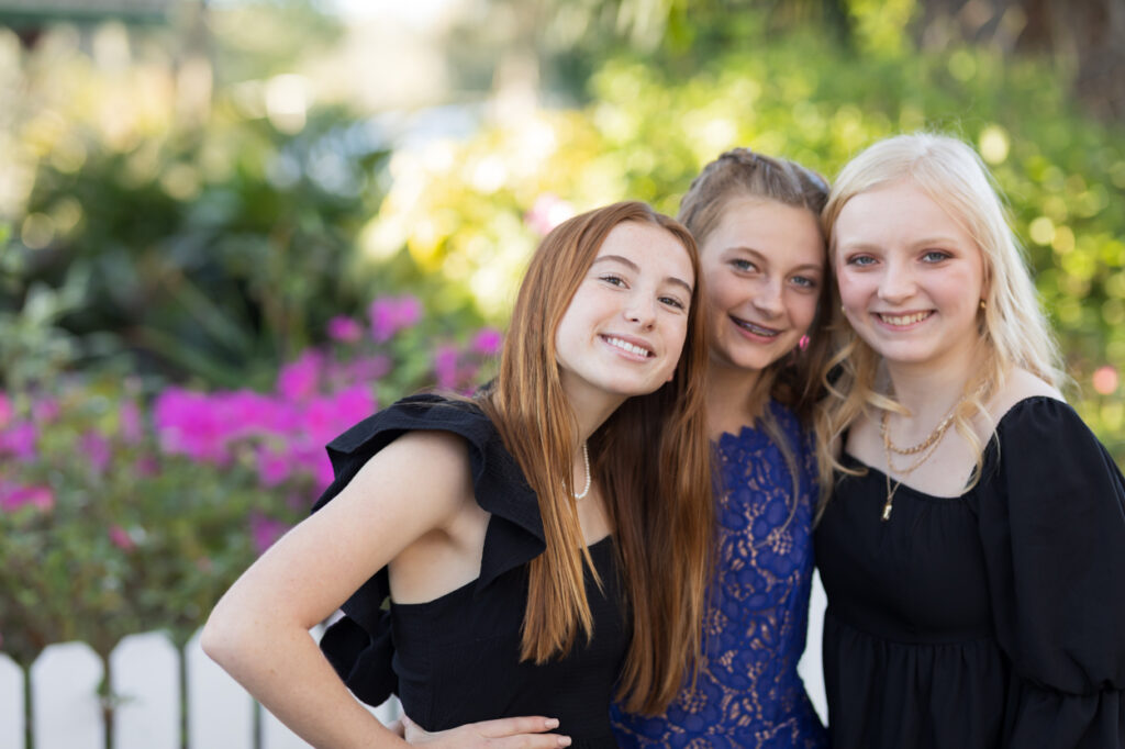 3 friends smiling in front of pink flowers