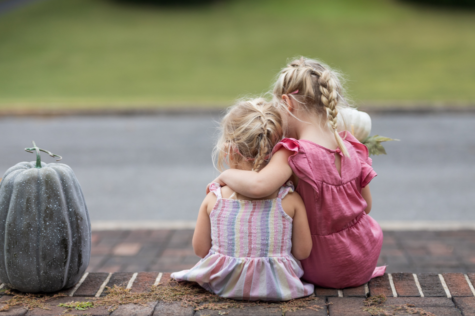 sisters sitting on the steps, back facing the camera