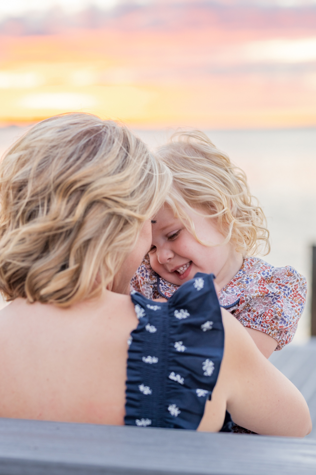 mom and daughter giggling with sunset