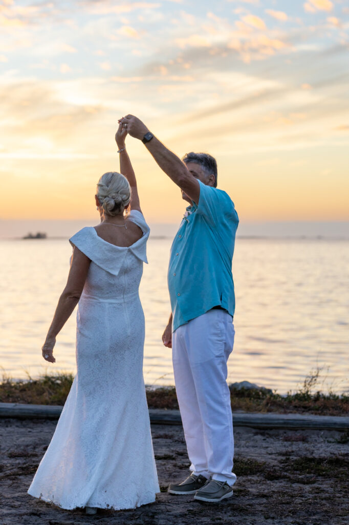 man twirling his wife at the beach