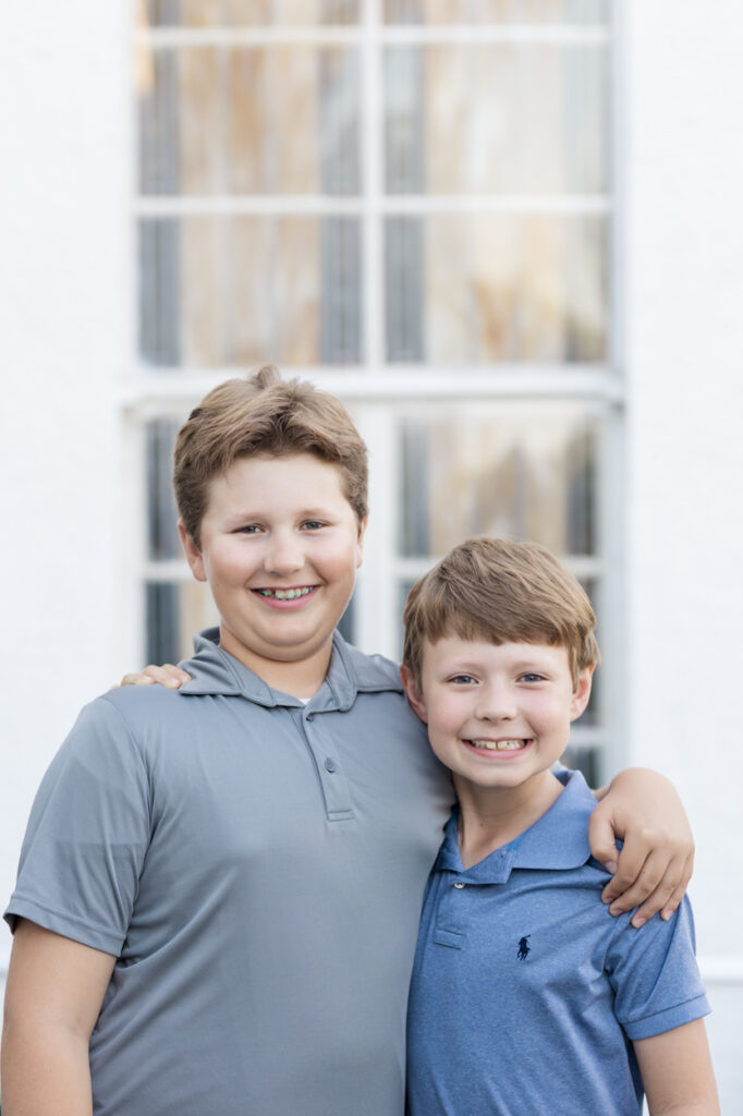 two boys smiling in front of stained glass window