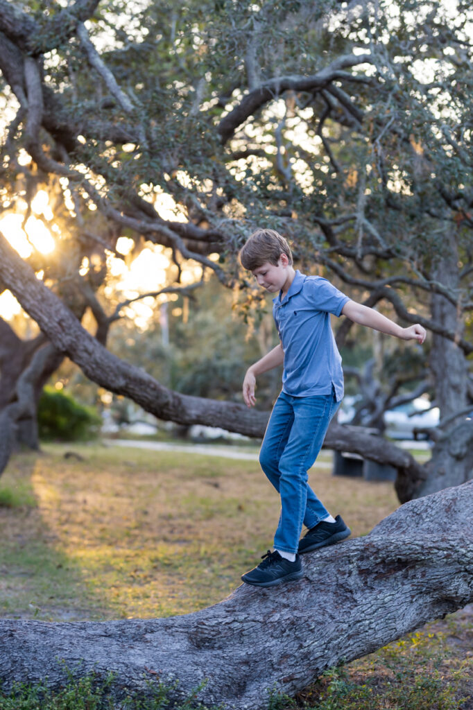 boy walking down large tree limb