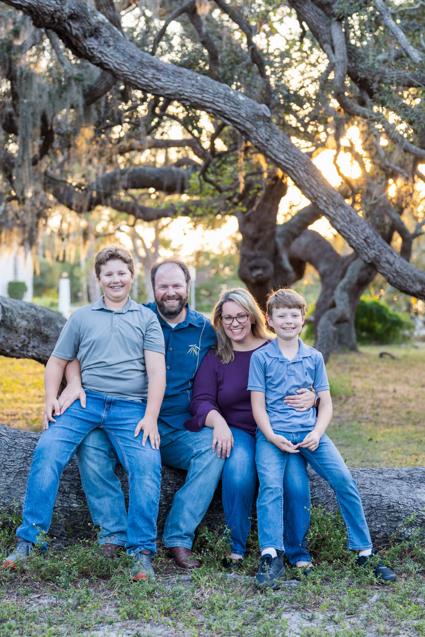 family of 4 sitting on a low tree branch