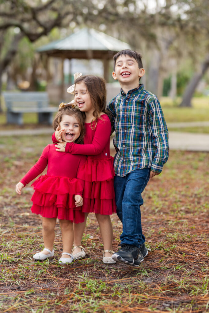 3 siblings smiling in a park