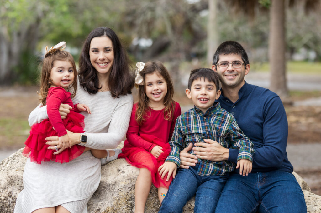 family of 4 posing by a large tree