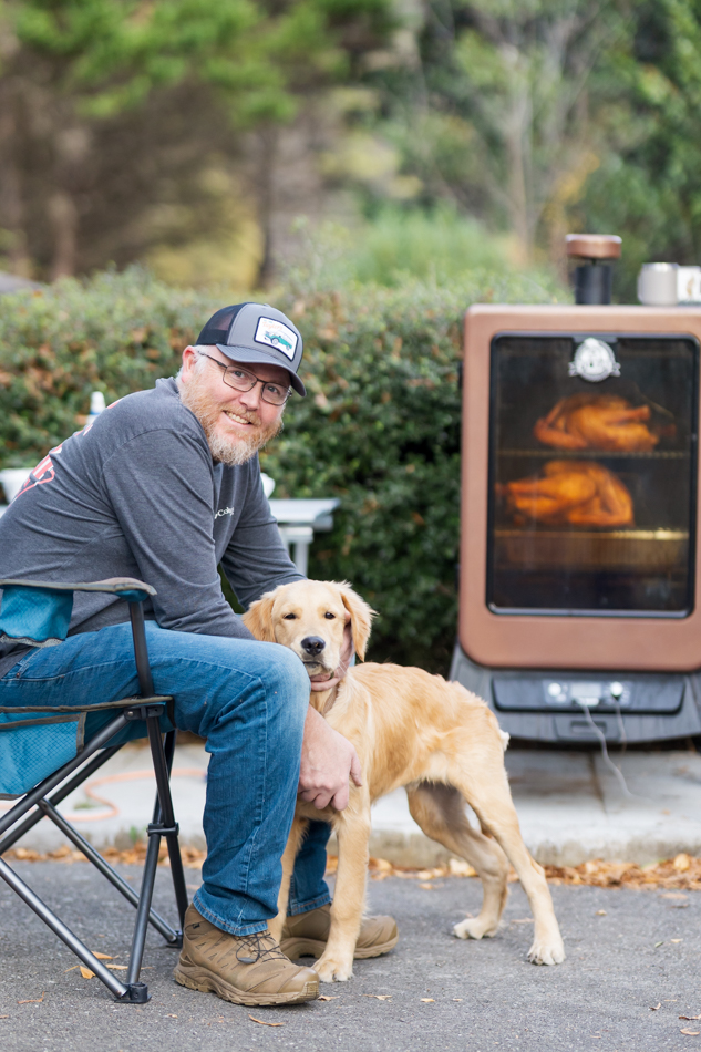 man petting his dog while he cooks.