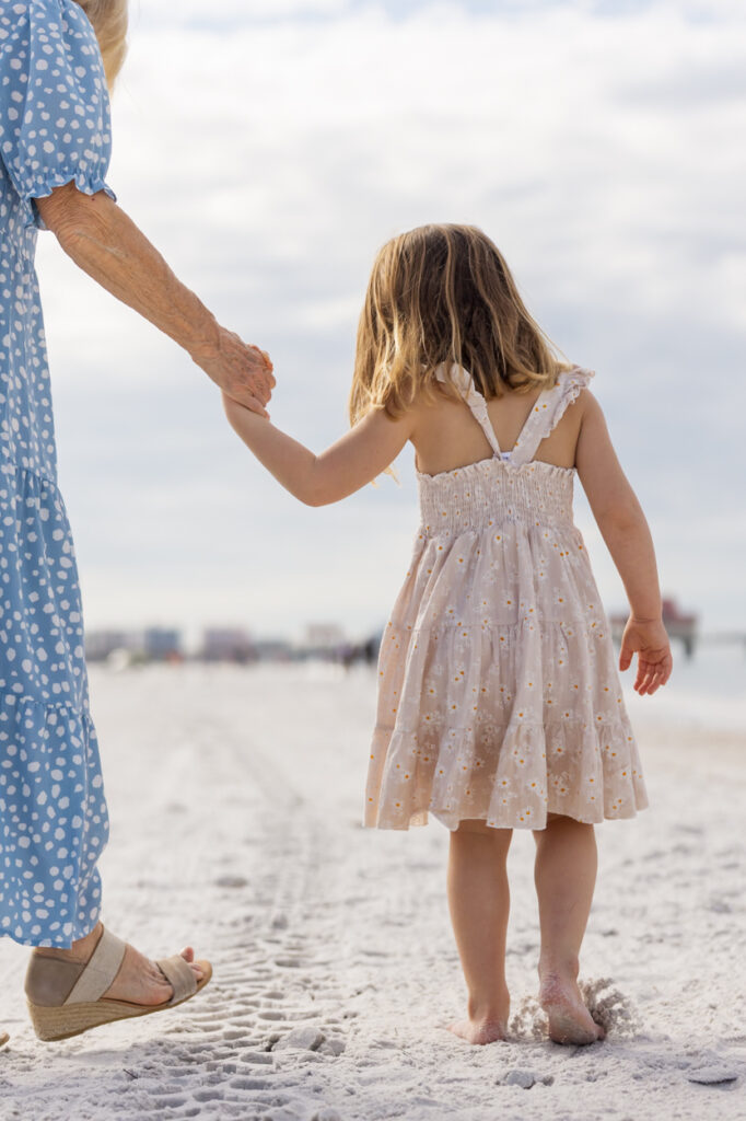 granddaughter holding grandma's hand at beach