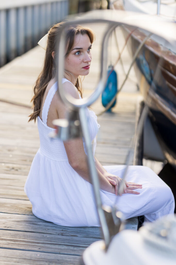girl sitting on the dock framed through boat rails