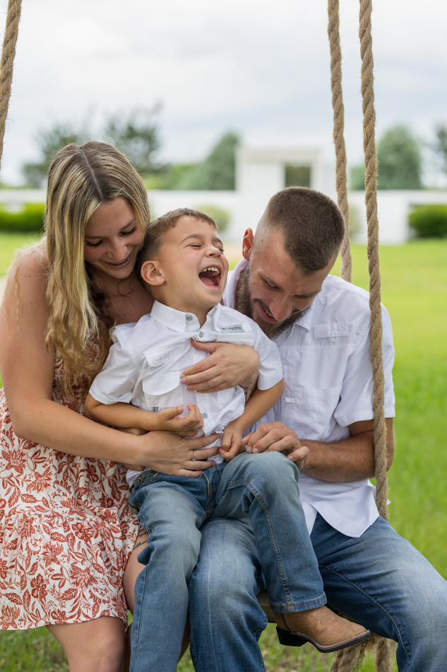 family laughing on tree swing