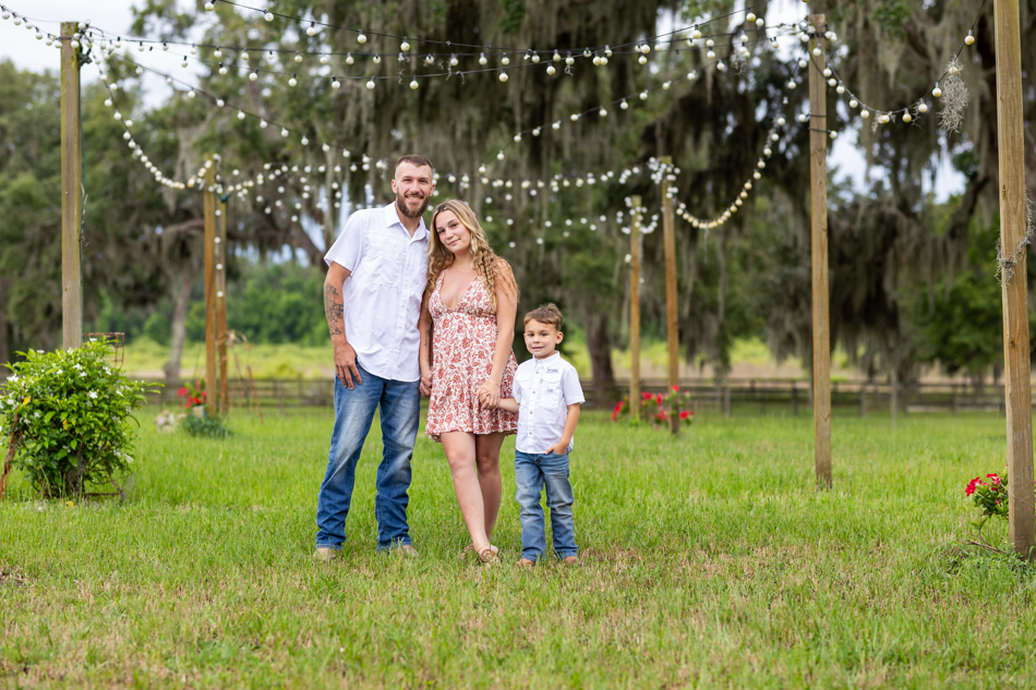family of three posing in front of twinkle lights