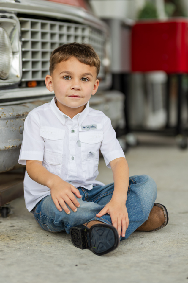 boy sitting in front of vintage car