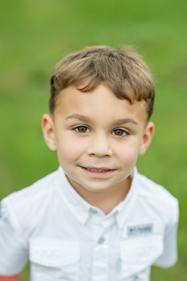 close up portrait of boy against green grass