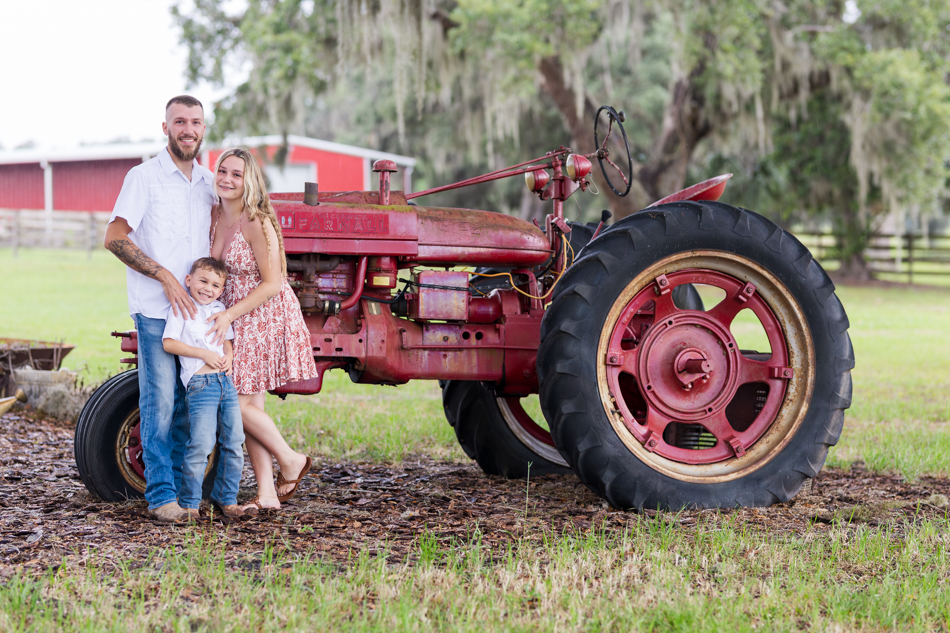 family posing in front of red tractor