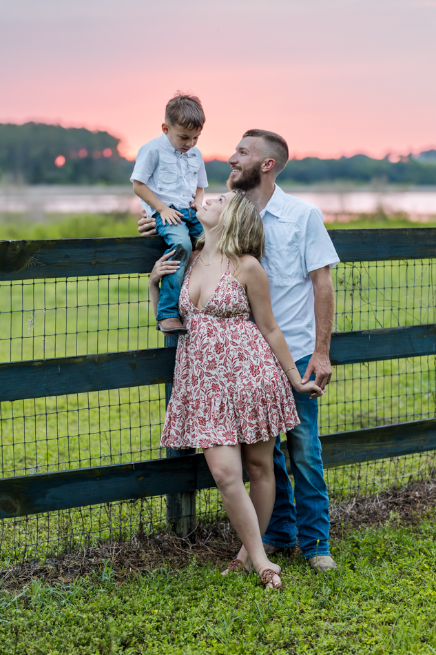 family on fenceline with sunset