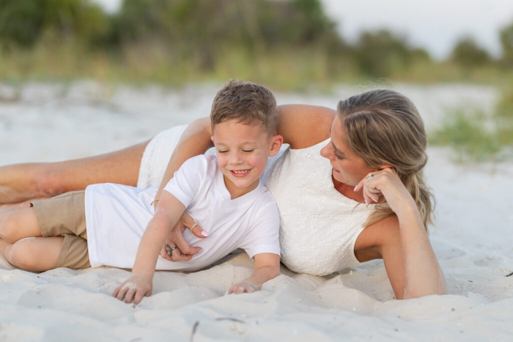 mom and son laying together in the sand